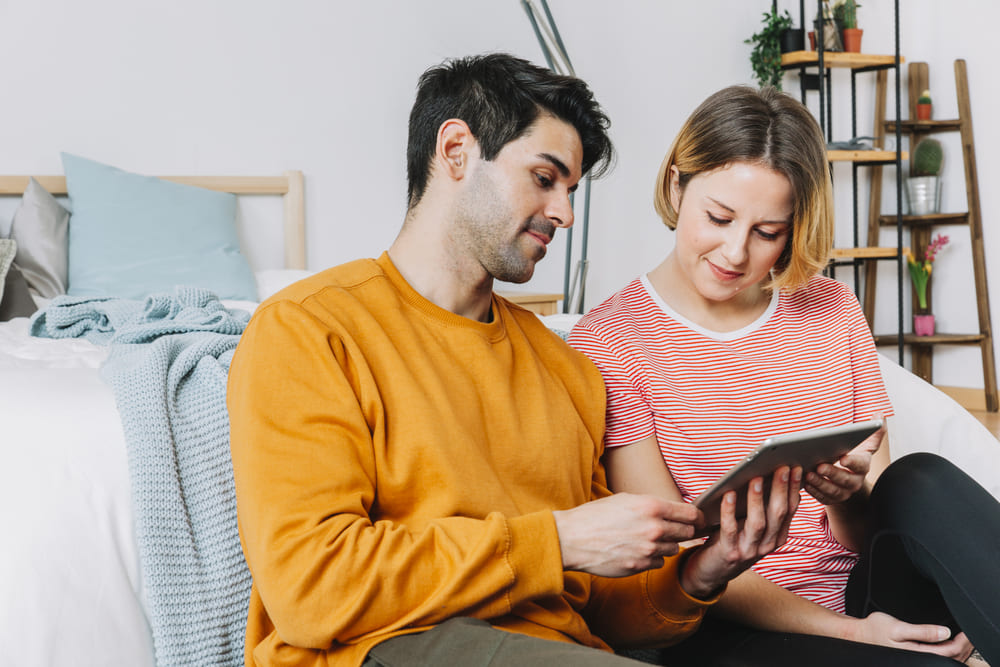 beautiful couple using tablet near bed